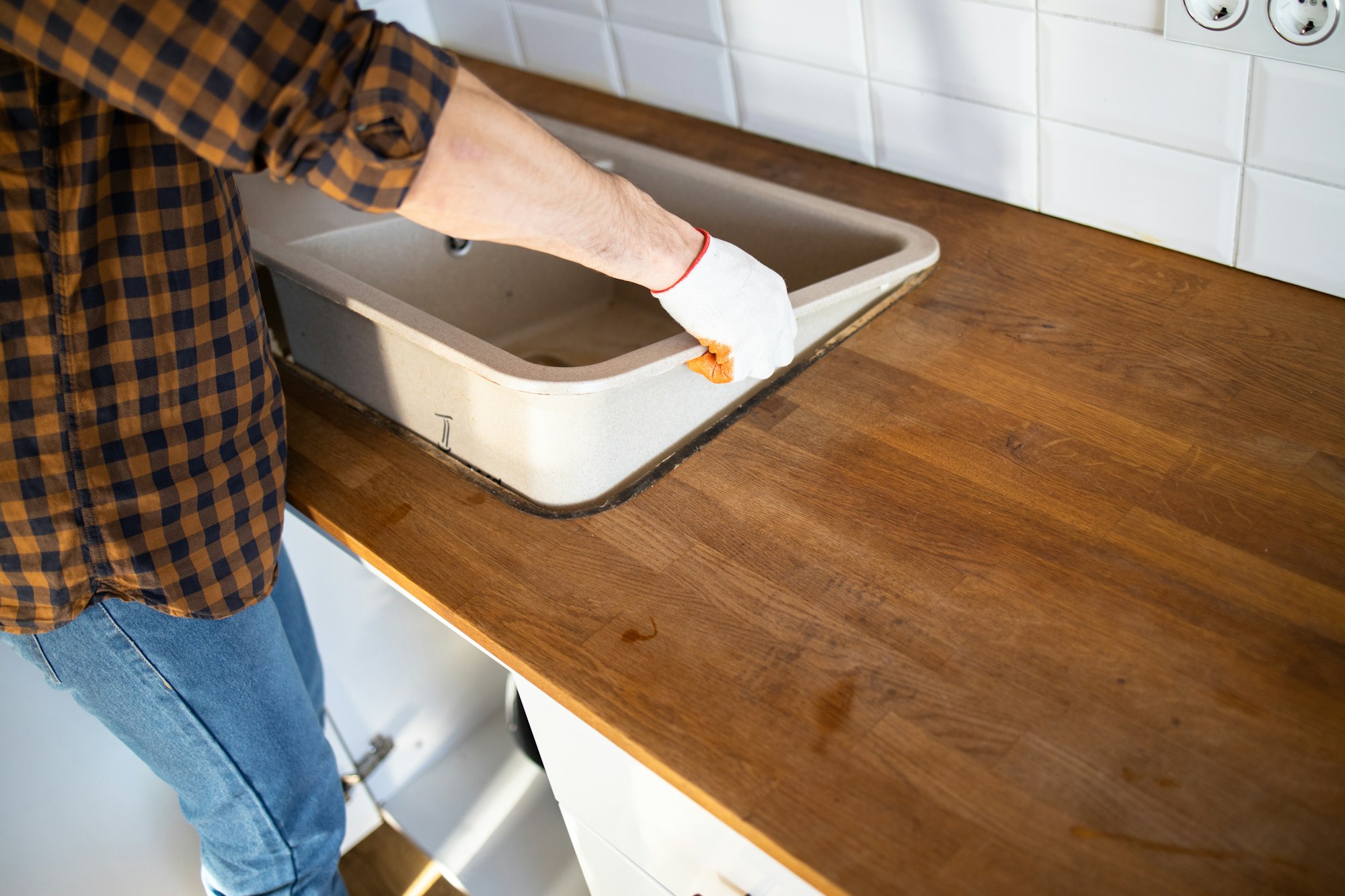 A man installs a sink in the kitchen. Assembly of kitchen furniture.